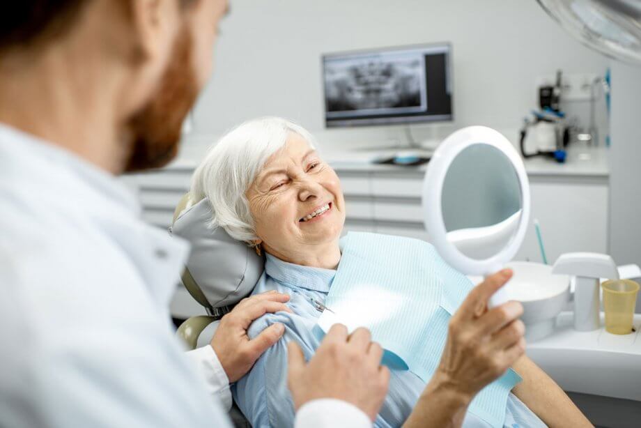 mature woman smiling with a handheld mirror