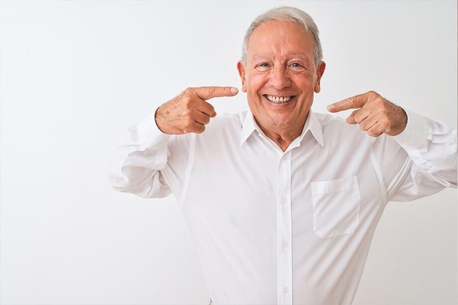 mature man smiling and pointing at his teeth