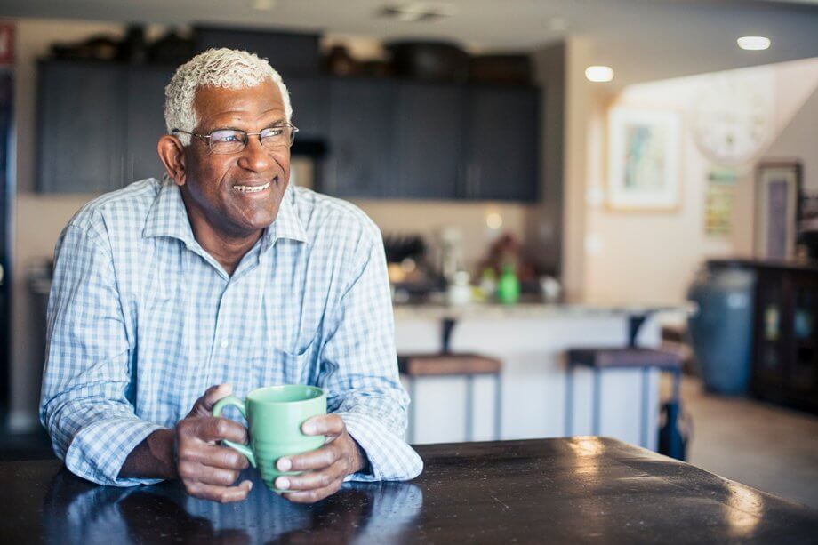Man smiles while holding a coffee cup