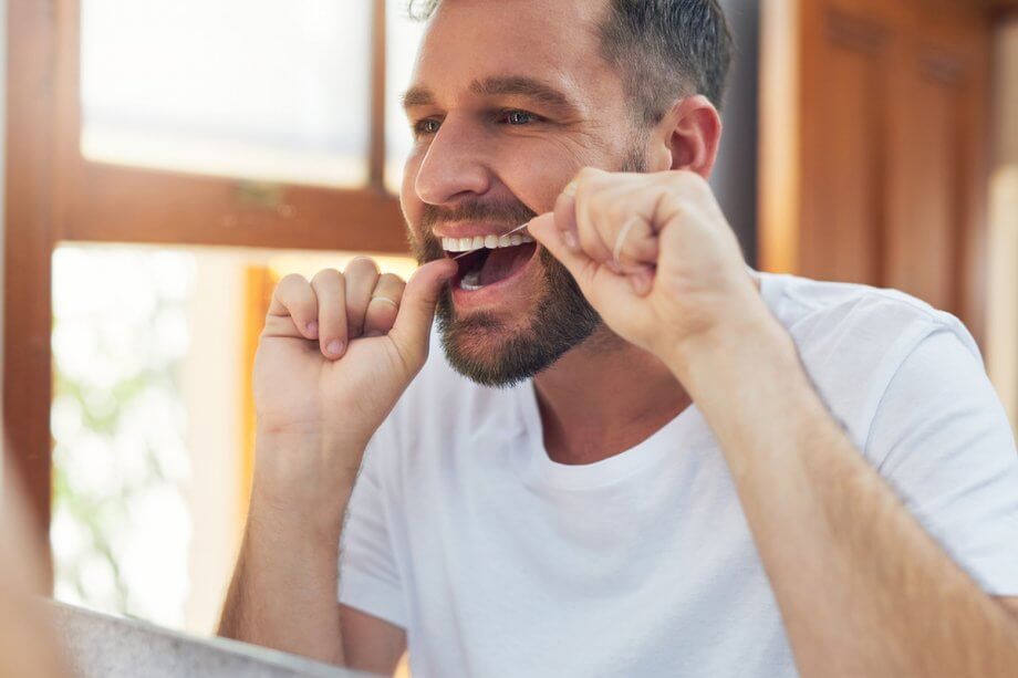 man flossing his teeth